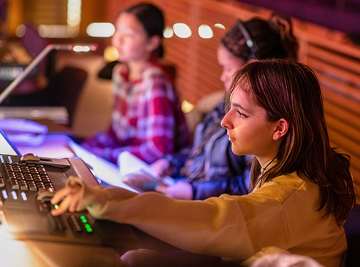 Students working lights and sound board for a theater performance