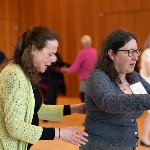 a woman in green sweater showing another woman how to dance