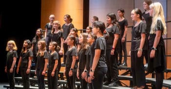 group of students standing on risers singing