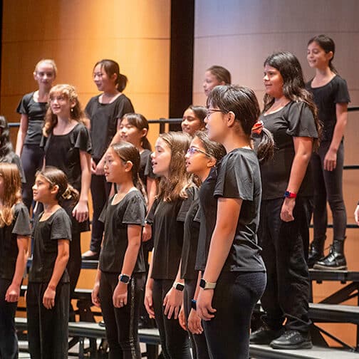 group of students standing on risers singing