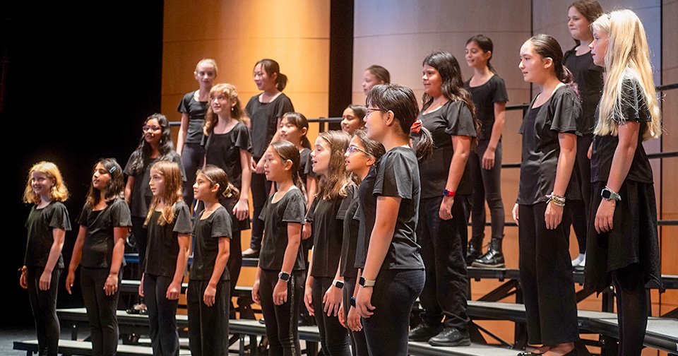 group of students standing on risers singing