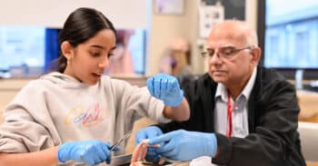 A grandfather and granddaughter doing a chicken wing dissection in science class.