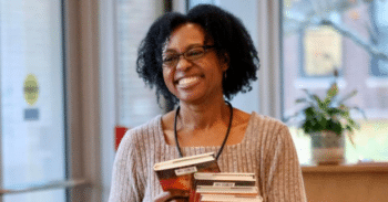 Female author holds a stack of books