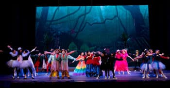 students on stage dancing dressed in colorful costumes