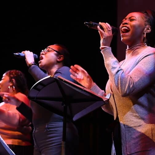 Four vocalists singing on stage.