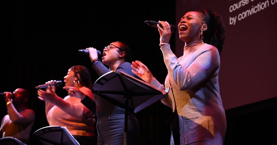 Four vocalists singing on stage.